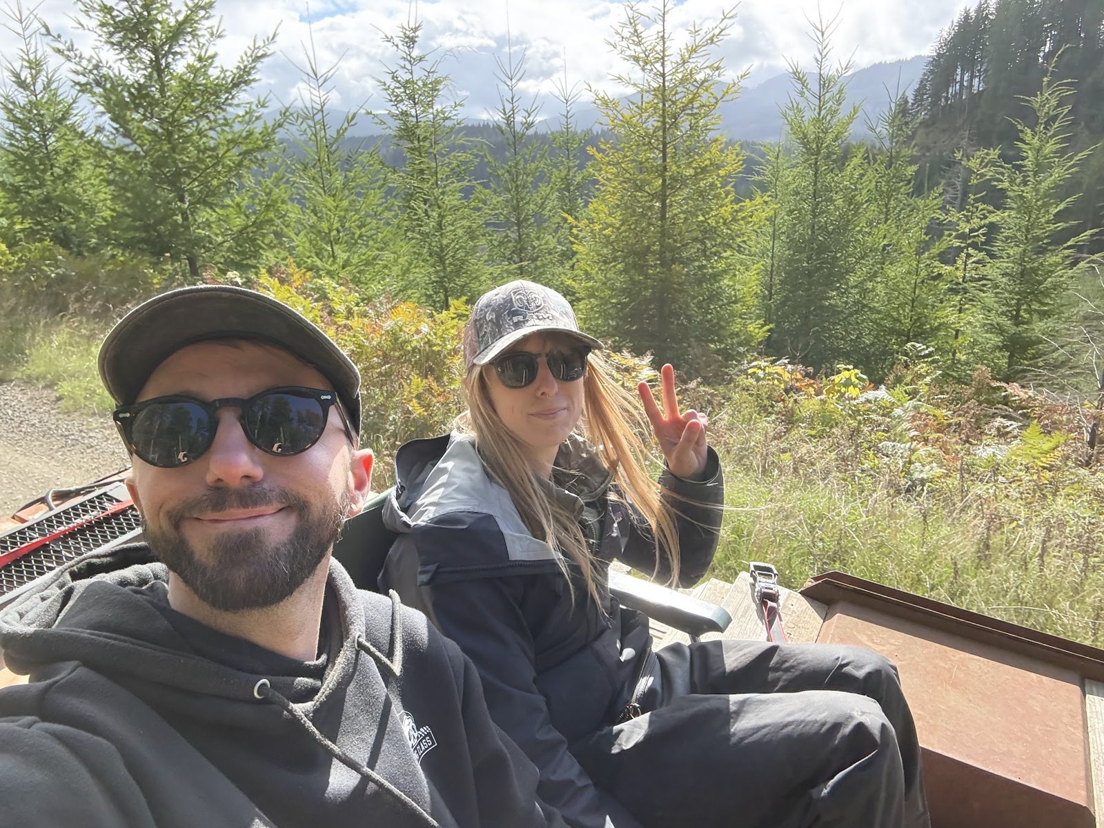 Two crew members smiling with forested hills behind them